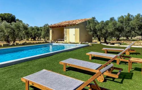 une arrière-cour avec une piscine bordée de bancs et une maison dans l'établissement Amazing Home In Maussane-Les-Alpilles, à Maussane-les-Alpilles