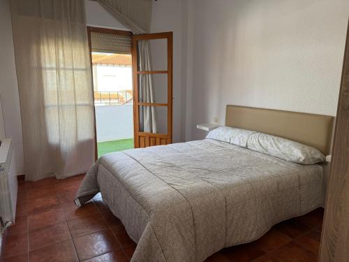 a bedroom with a bed and a door to a balcony at Cantarranas in Los Hinojosos