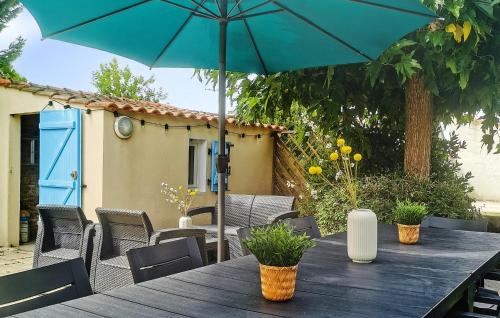- une table en bois avec un parasol sur la terrasse dans l'établissement Cozy Home In Laiguillon La Presquile, à LʼAiguillon-sur-Mer