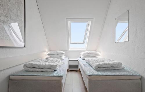 two twin beds in a room with two windows at Stunning Home In Gudhjem With Sauna in Gudhjem