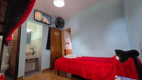a bedroom with a red bed and a bathroom at Hotel y Restaurant AKATA in Río Mayo