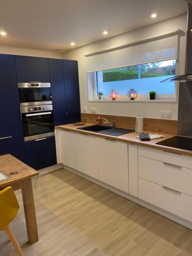 d'une cuisine avec des placards blancs, une fenêtre et un évier. dans l'établissement Villa Les Sables, à Condette