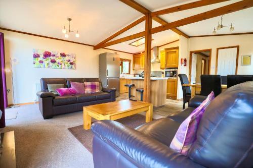 a living room with leather couches and a table at Devon Comfort Lodge with Hot Tub - Spa Resort in Devon in Chudleigh