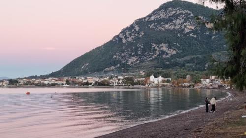 two people walking on the beach with a mountain in the background at Gentle Breeze apartment in Kamena Vourla