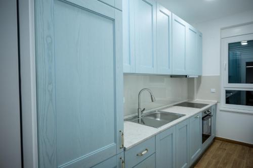 a kitchen with white cabinets and a sink and a window at LUST PREMIUM Apartments IV CENTER PARK in Kragujevac