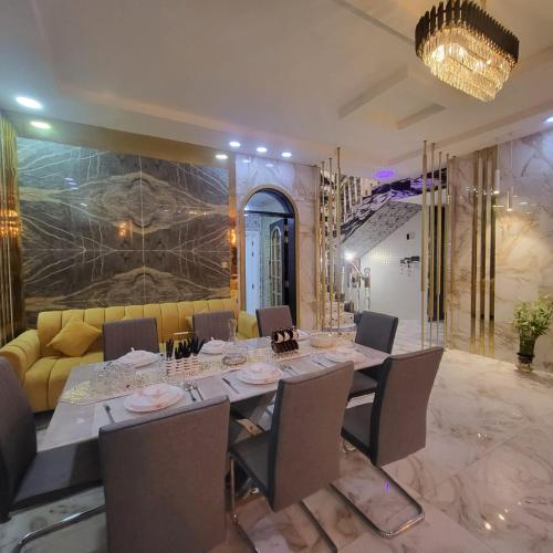 a dining room with a long table and a yellow couch at Beachfront Holiday Homes in Ajman 