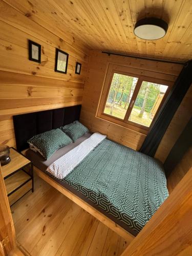 a small room with a bed in a cabin at DOMEK W BRZOZACH nad jeziorem z balią na wyłączność in Lgiń