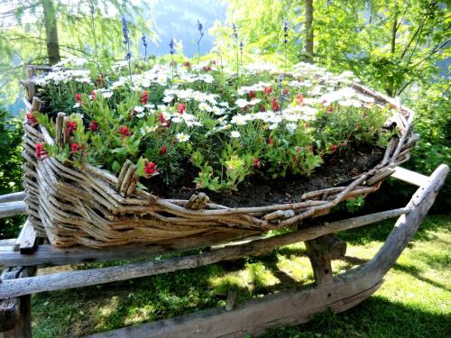 a basket filled with flowers on a wooden bench at Charmehotel Uhrerhof - Deur in Ortisei