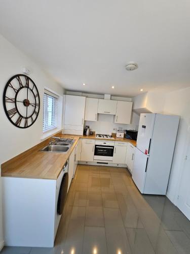 a kitchen with white appliances and a clock on the wall at Spacious 2 BEDROOM HOUSE in Dartford in Dartford