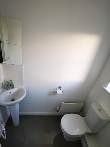 a white bathroom with a toilet and a sink at Spacious 2 BEDROOM HOUSE in Dartford in Dartford