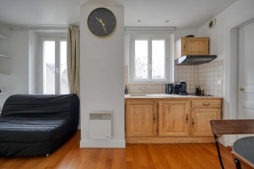 une cuisine avec une grande horloge murale dans l'établissement L'Auguste - 10mn Paris - Proche Gare, à Maisons-Alfort