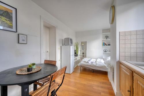 une cuisine et une salle à manger avec une table et un réfrigérateur dans l'établissement L'Auguste - 10mn Paris - Proche Gare, à Maisons-Alfort