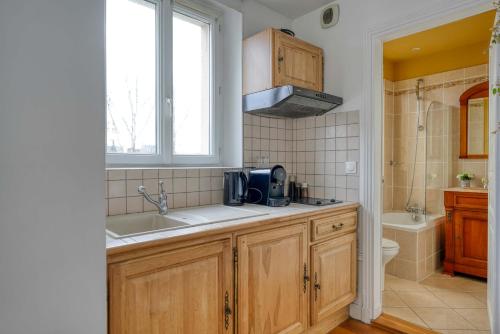 une cuisine avec un évier et un micro-ondes dans l'établissement L'Auguste - 10mn Paris - Proche Gare, à Maisons-Alfort