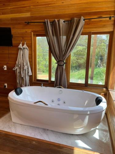 a large white bath tub in a room with windows at Pousada e fazenda mato verde in São Bonifácio
