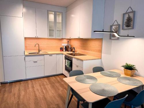 eine Küche mit weißen Schränken und Holztischen und -stühlen in der Unterkunft Apt 555 New & Fully Equipped with Free Garage in Bratislava