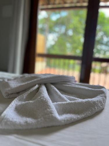 a towel sitting on top of a bed with a window at Pousada Vilarejo in Itacaré