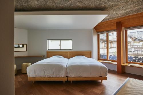 a bedroom with a large bed with white sheets at TSUCHIYA Kinosaki onsen in Toyooka