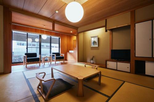 a living room with a table and a tv at TSUCHIYA Kinosaki onsen in Toyooka