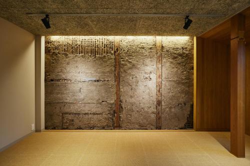 an empty room with a stone wall with lights at TSUCHIYA Kinosaki onsen in Toyooka
