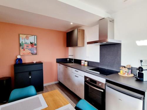 une cuisine avec des murs orange et un comptoir noir dans l'établissement Charmant T2 neuf haut de gamme, à Brive-la-Gaillarde