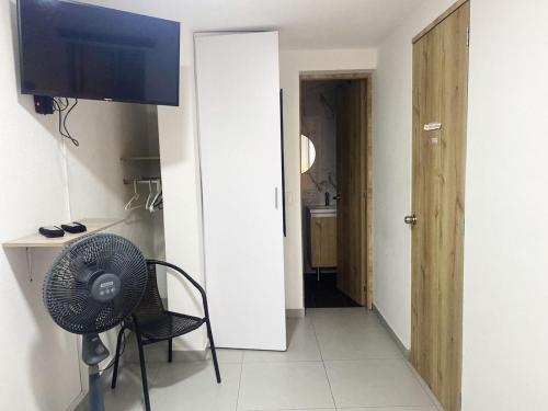 a room with a fan and a chair and a television at Hotel Boutique San Joaquin Plaza in Medellín