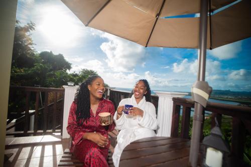 two women sitting on a porch with an umbrella at Buena Vista SLC in Vieux Fort