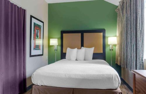 a bed in a hotel room with green walls at Extended Stay America Suites - Dallas - Plano Parkway in Plano