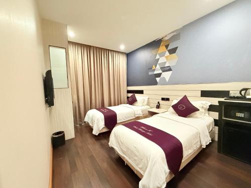 a hotel room with two beds and a television at Venus Boutique Hotel in Melaka