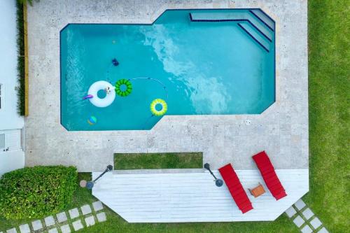 an overhead view of a swimming pool with two red chairs and a swimming pool at Casa Cabos - Fun in Miami - Pool BBQ - Fit 10 in Tamiami