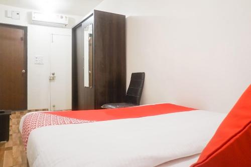 a bedroom with a white bed and a black chair at Super Hotel O River View Near Shaniwar Wada in Pune