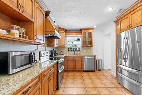 a kitchen with wooden cabinets and stainless steel appliances at Casa Cabos - Fun in Miami - Pool BBQ - Fit 10 in Tamiami