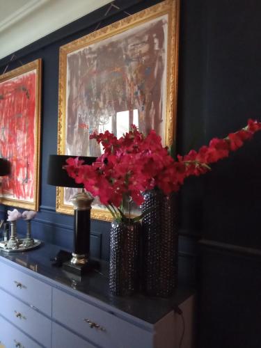 a vase of red flowers on a dresser in a room at Room B - Louvre Museum in Paris