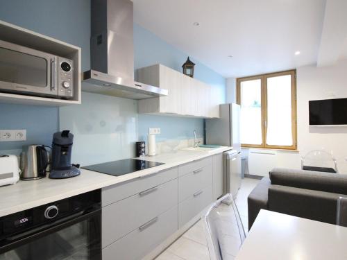 une cuisine avec des armoires blanches et un micro-ondes dans l'établissement Bel F2 au 3e étage avec ascenseur, parking privé, wifi, cuisine équipée et local à skis - Mont-Dore - FR-1-415-70, à Le Mont-Dore