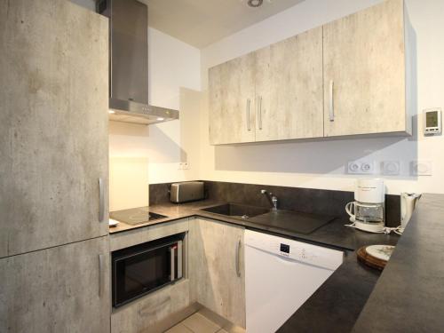 une cuisine avec des armoires blanches et un évier dans l'établissement Bel F3 au 2ème étage, à 50m des Thermes, bien équipé, 6 couchages, idéal pour cures et vacances - FR-1-415-65, à Le Mont-Dore