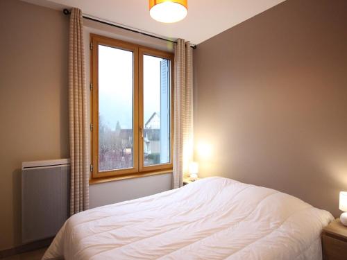 une chambre avec un lit blanc et une fenêtre dans l'établissement Appartement F2 de 28m² avec Parking Privé, Wifi et Ascenseur, à 200m des Thermes au Mont-Dore. - FR-1-415-68, à Le Mont-Dore