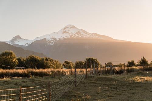 a mountain in the distance with a fence in a field at Puerta austral in Puelo