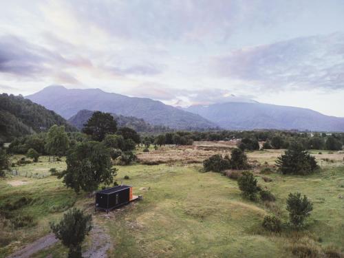 a small shack in a field with mountains in the background at Puerta austral in Puelo