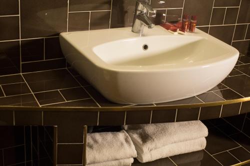 a bathroom with a sink and towels on a shelf at B&B 7 Vizi in Colà di Lazise