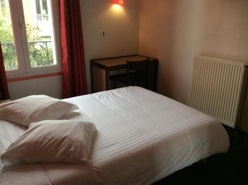 ein Schlafzimmer mit einem großen weißen Bett und einem Fenster in der Unterkunft Hotel De La Place in Malakoff