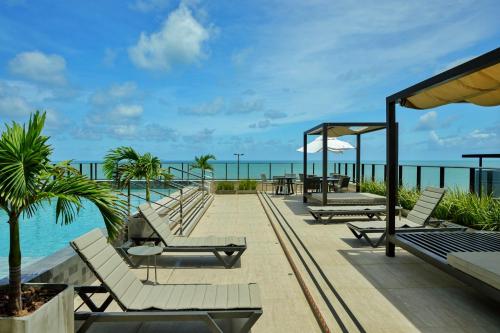 Una terraza con tumbonas y el océano. en Meu Aconchego à Beira Mar - Exclusivo - Praia Jardim Oceania - João pessoa, en João Pessoa