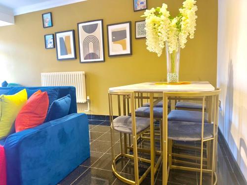 a table with a vase of flowers and two blue chairs at Your next room in Portsmouth in Portsmouth