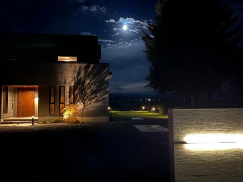 a building at night with the moon in the sky at Blooming Villa Higashikawa in Higashikawa