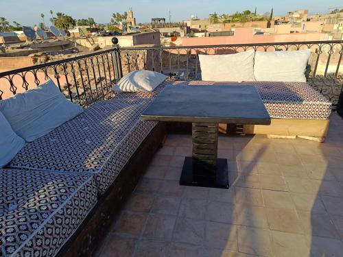 a patio with two beds and a table on a balcony at Riad Palais Bahia - Entire House - 5 Bedrooms in Marrakech