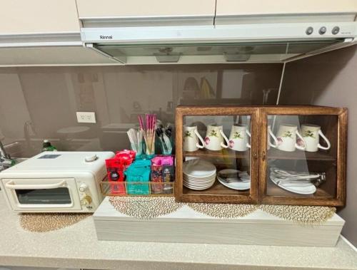 a cabinet with plates and cups and a microwave at Ling Lai B&B in Neipu
