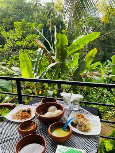 a table with plates of food on a balcony at Rainforest Mask villa in Deniyaya