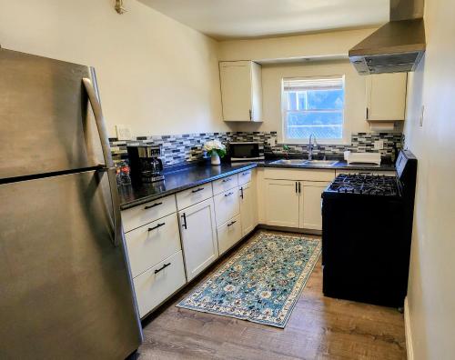 a kitchen with white cabinets and a black refrigerator at LAX House Near SoFi Stadium, Intuit Dome, YouTube Theater, The Kia Forum, Beaches in Inglewood