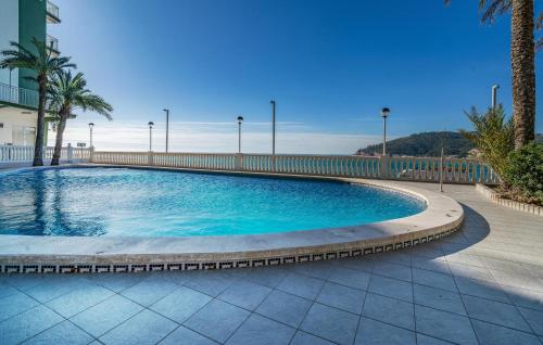 a swimming pool with blue water and palm trees at Nice Apartment In Oropesa Del Mar in Oropesa del Mar