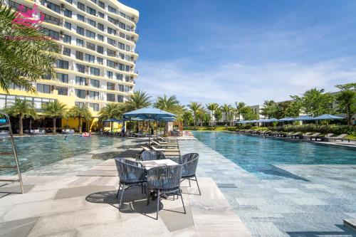 a swimming pool with chairs and a table and a building at Lux Resort Apartment/2BR/Private Beach/Pools in Hà My Tây (2)