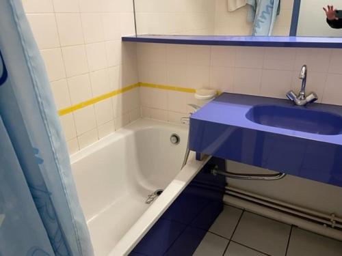 La salle de bains est pourvue d'un lavabo bleu et d'une baignoire. dans l'établissement Appartement à Arzon, terrasse, piscine, près thalassothérapie - FR-1-775-7, à Arzon