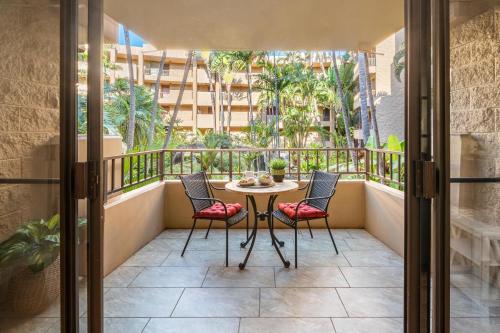 a balcony with a table and chairs and palm trees at Paki Maui 217 · PM 217 Cozy 1BR Oceanfront Condo w Pool in Lahaina